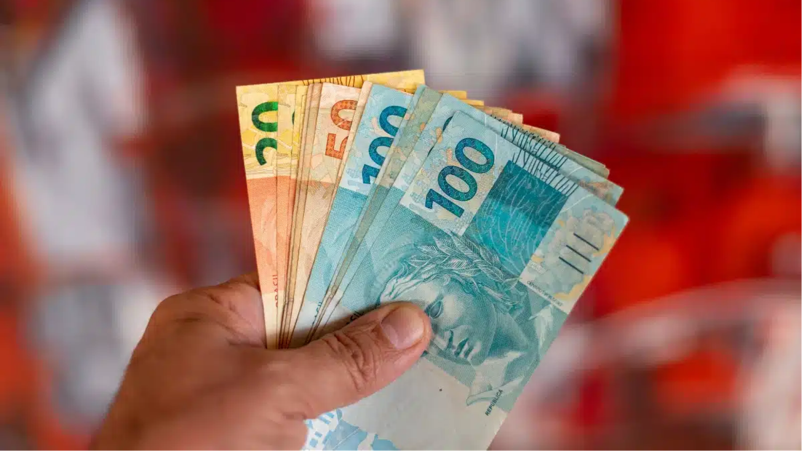 uma mão segurando um leque de dinheiro BRL